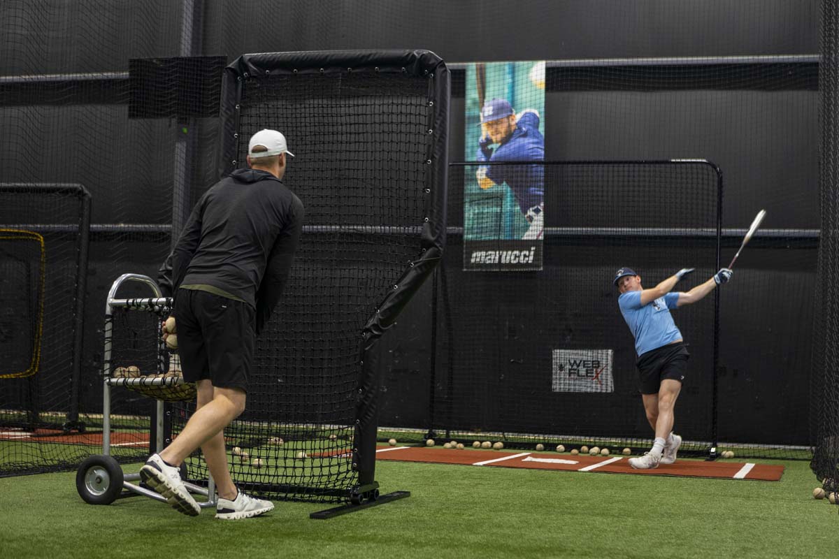 Parker bridwell throwing batting practice inside a baseball academy